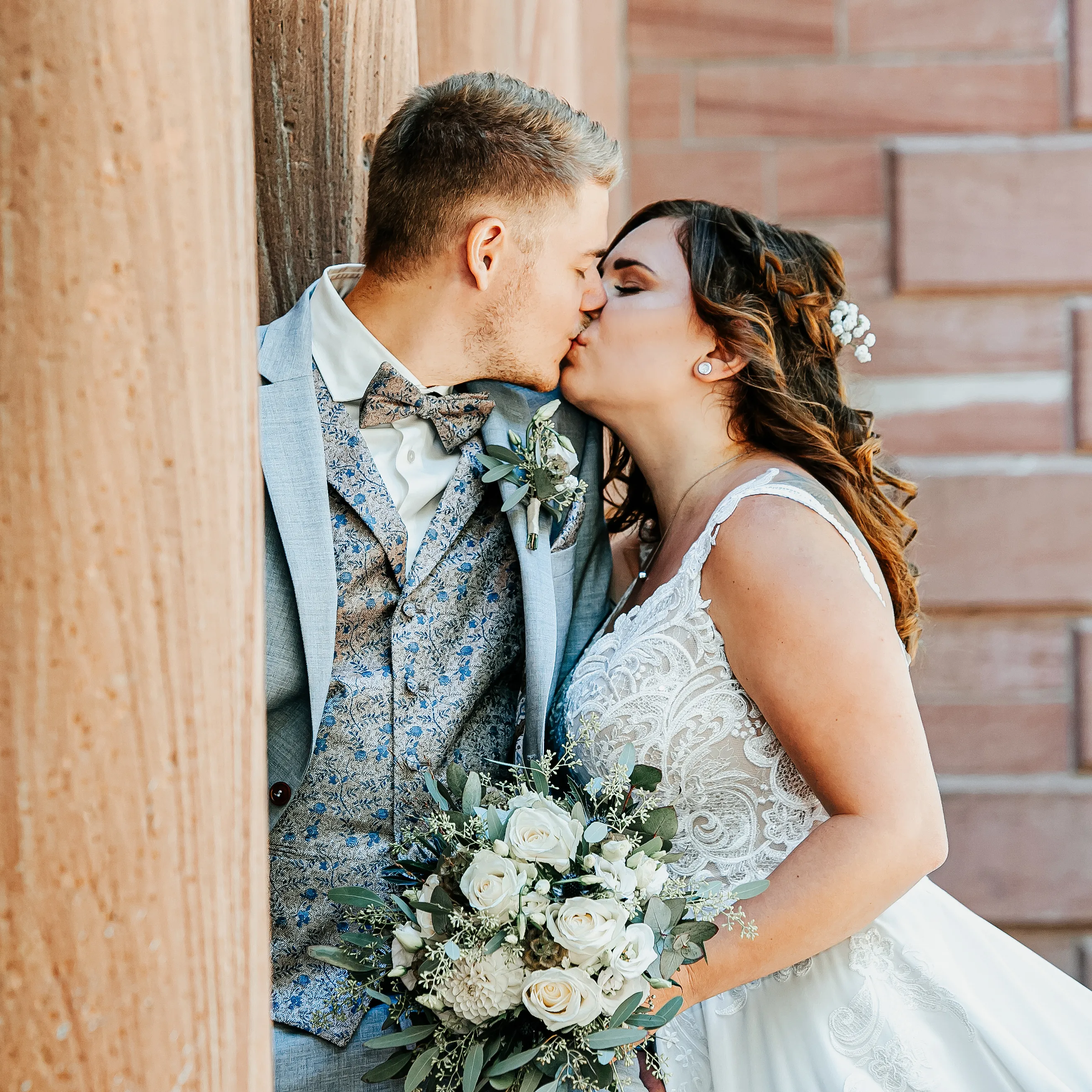 Sich küssendes Brautpaar vor Sandsteinmauer