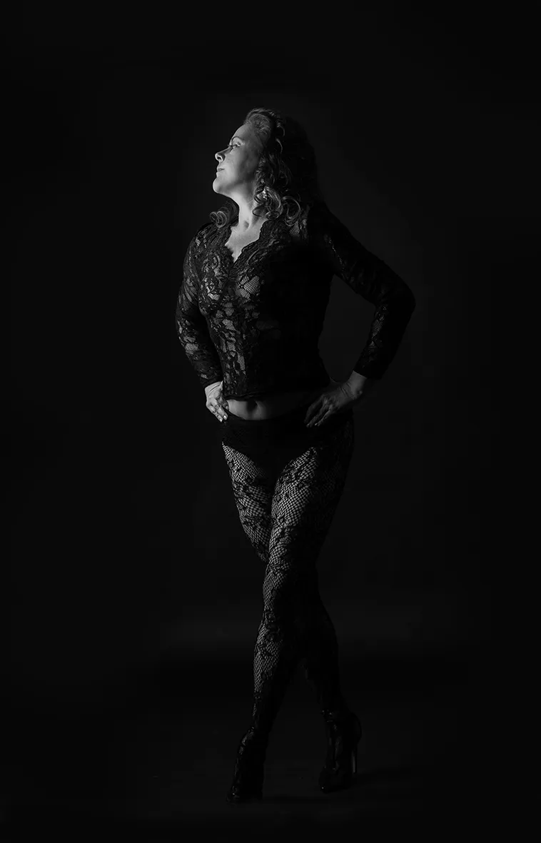 Frau stehend in Spitzenwäsche vor schwarzem Hintergrund