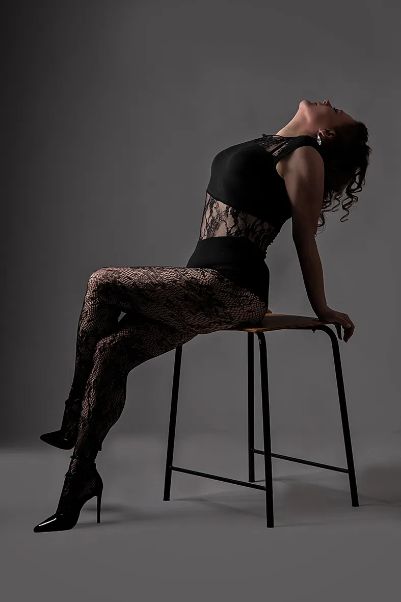 Frau in Spitzenwäsche auf Hocker abgestützt den Kopf in den Nacken gelegt