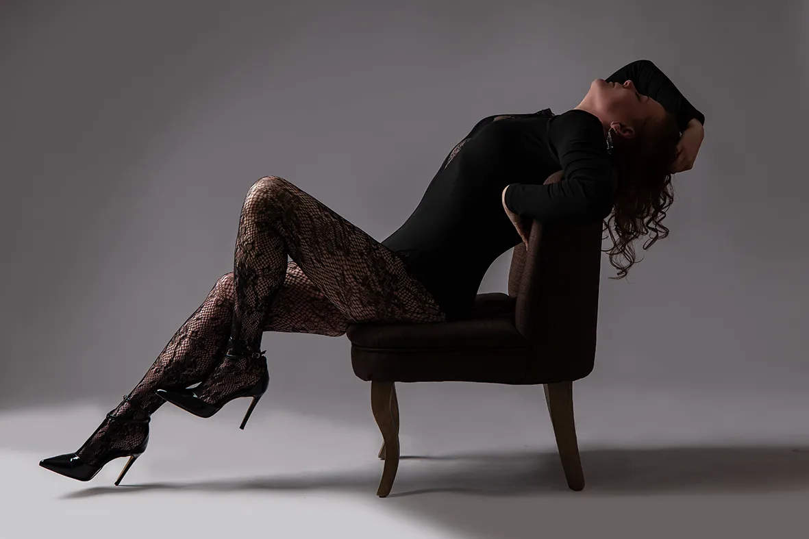 Frau auf Sessel in schwarzer Wäsche mit Kopf im Nacken