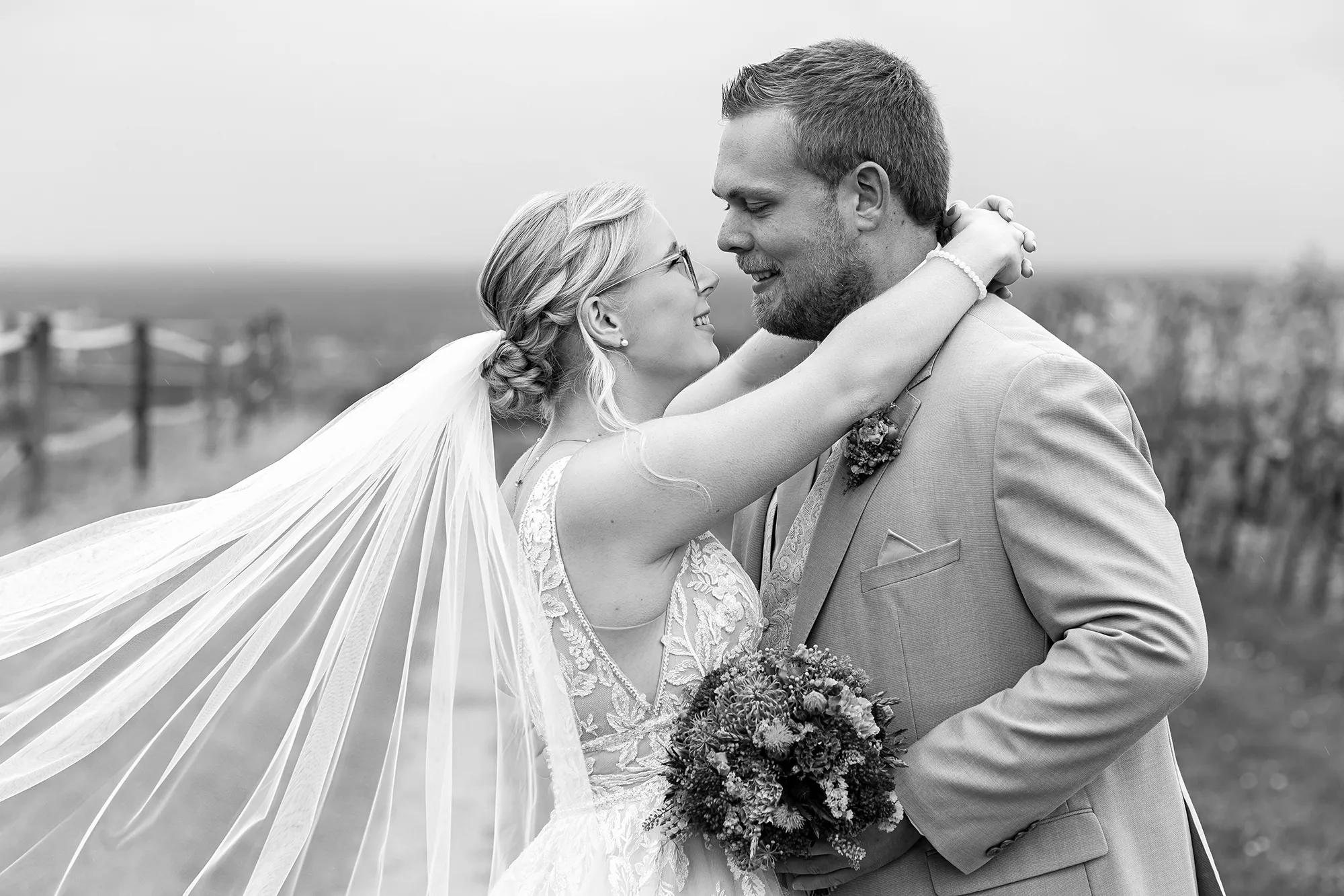 Brautpaar eng umschlungen mit wehendem Schleier