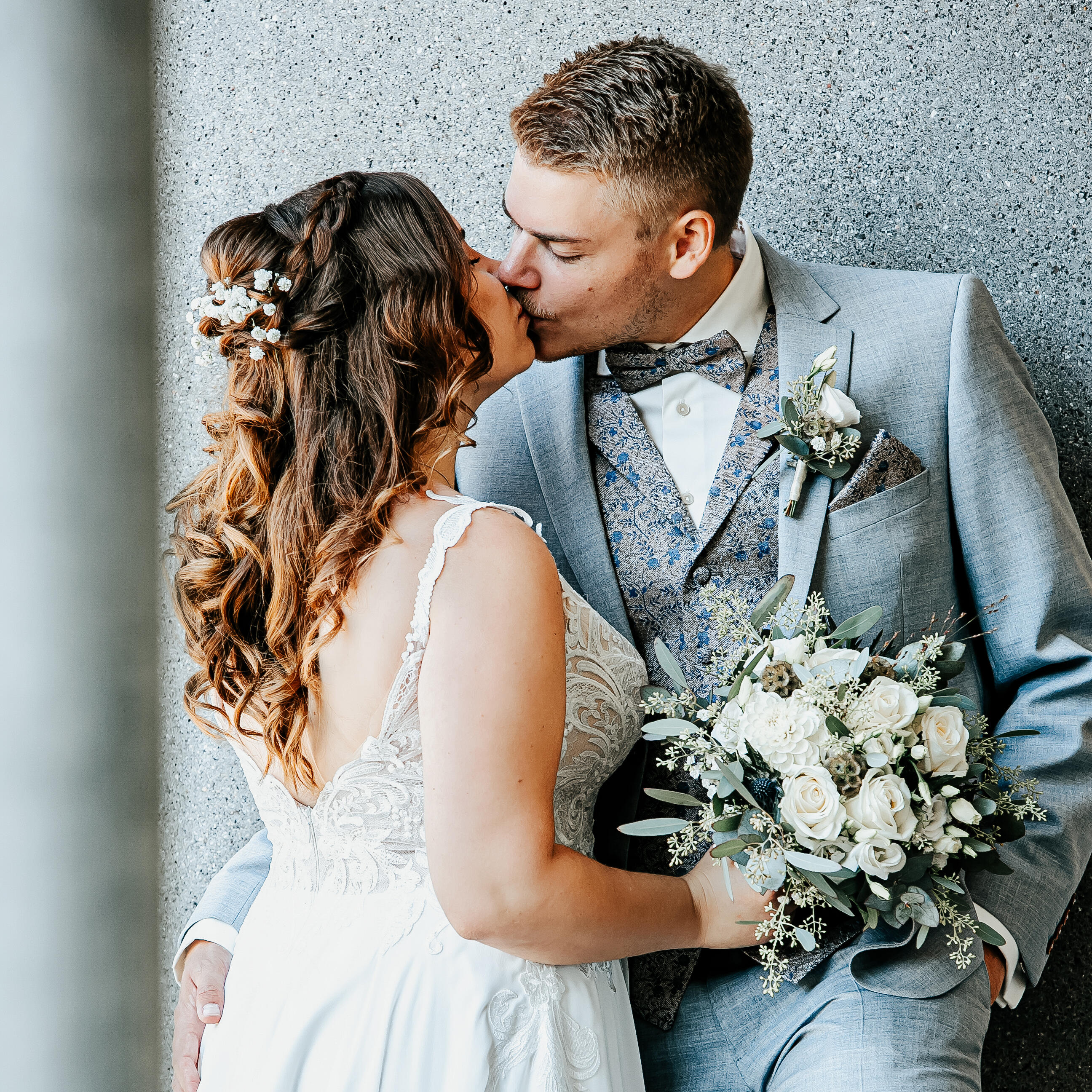 Küssendes Hochzeitspaar vor grauem Hintergrund